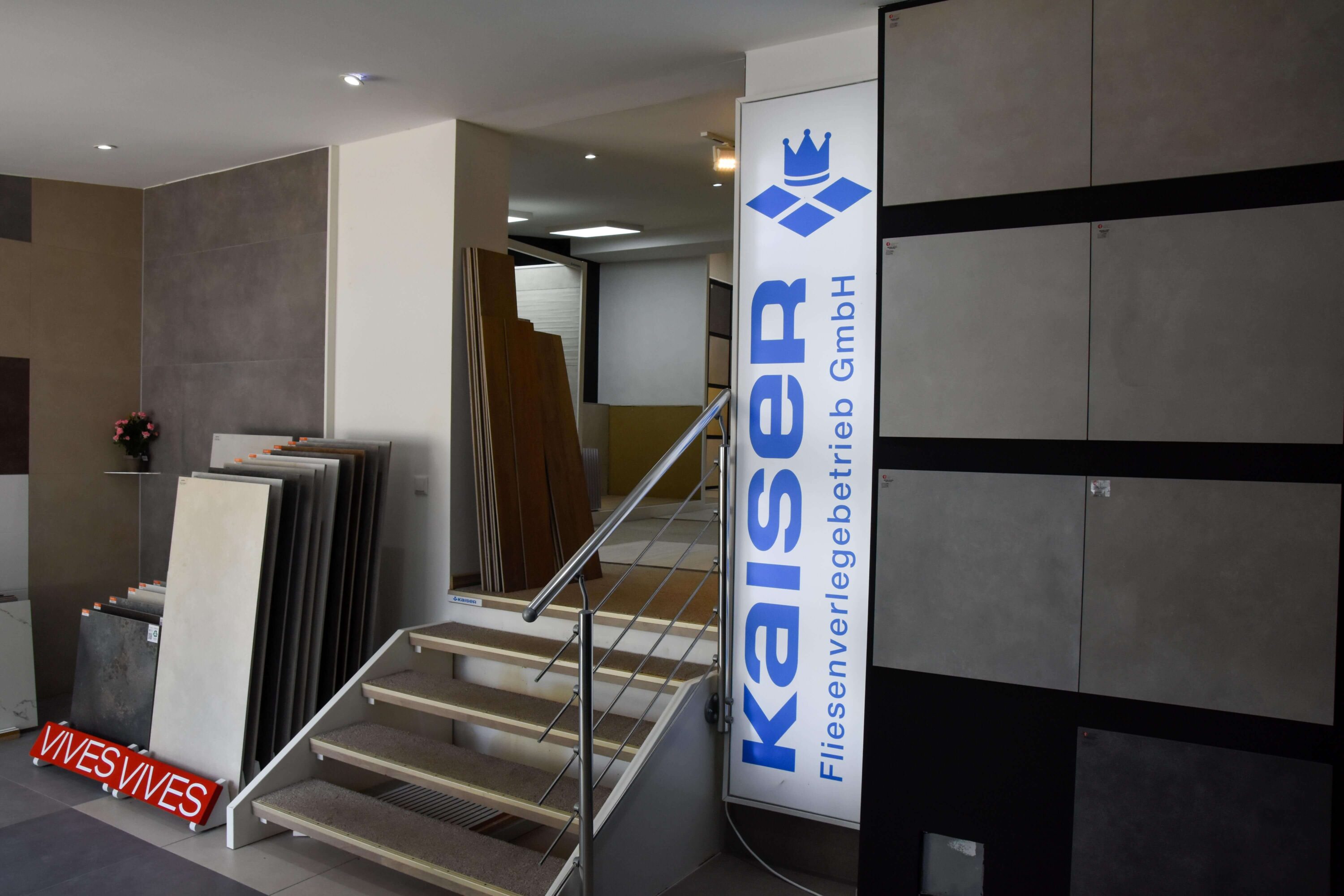 Fliesenausstellung von Kaiserfliesenverlegebetrieb, Fliesenleger aus Düsseldorf Gerresheim, mit Logo-Banner und Fliesen an der Wand
